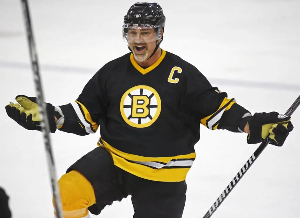 A Boston Bruins player celebrates after scoring a goal in Ray Bourque's hockey journey from humble beginnings to Hall of Fame glory.